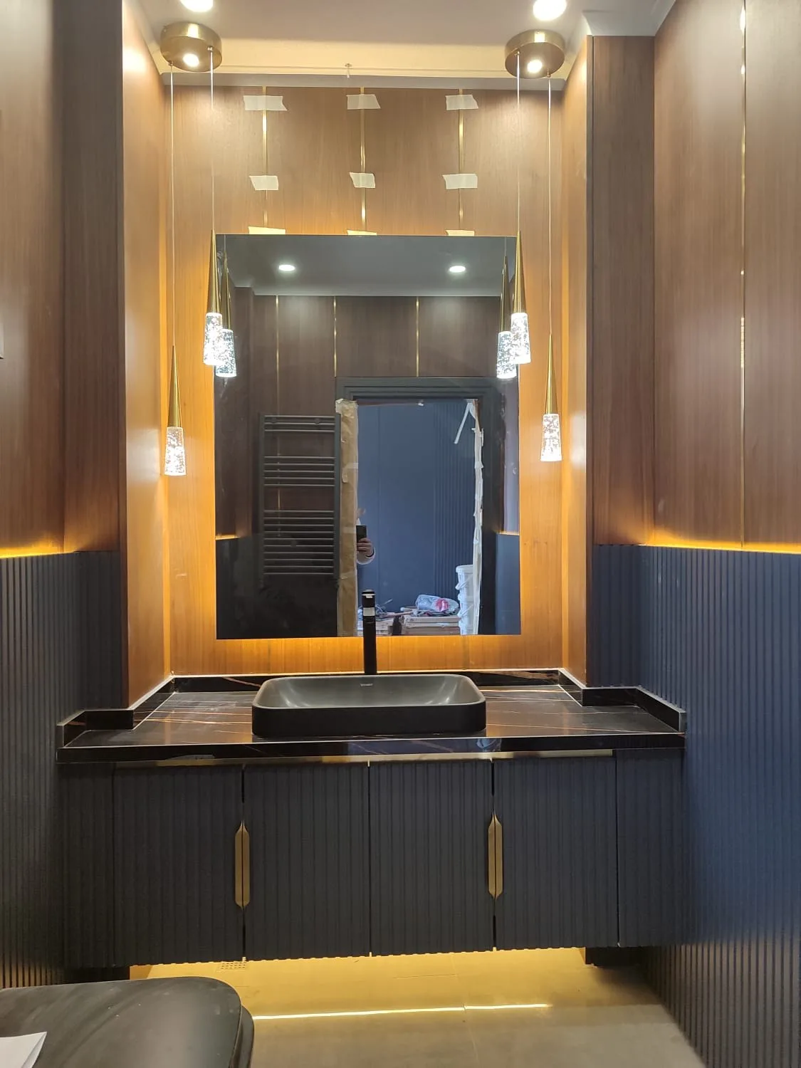 Ceviz panelli banyo; pirinç çıtalı duvar kaplaması, fileto kapaklı lavabo dolabı ve siyah tezgah