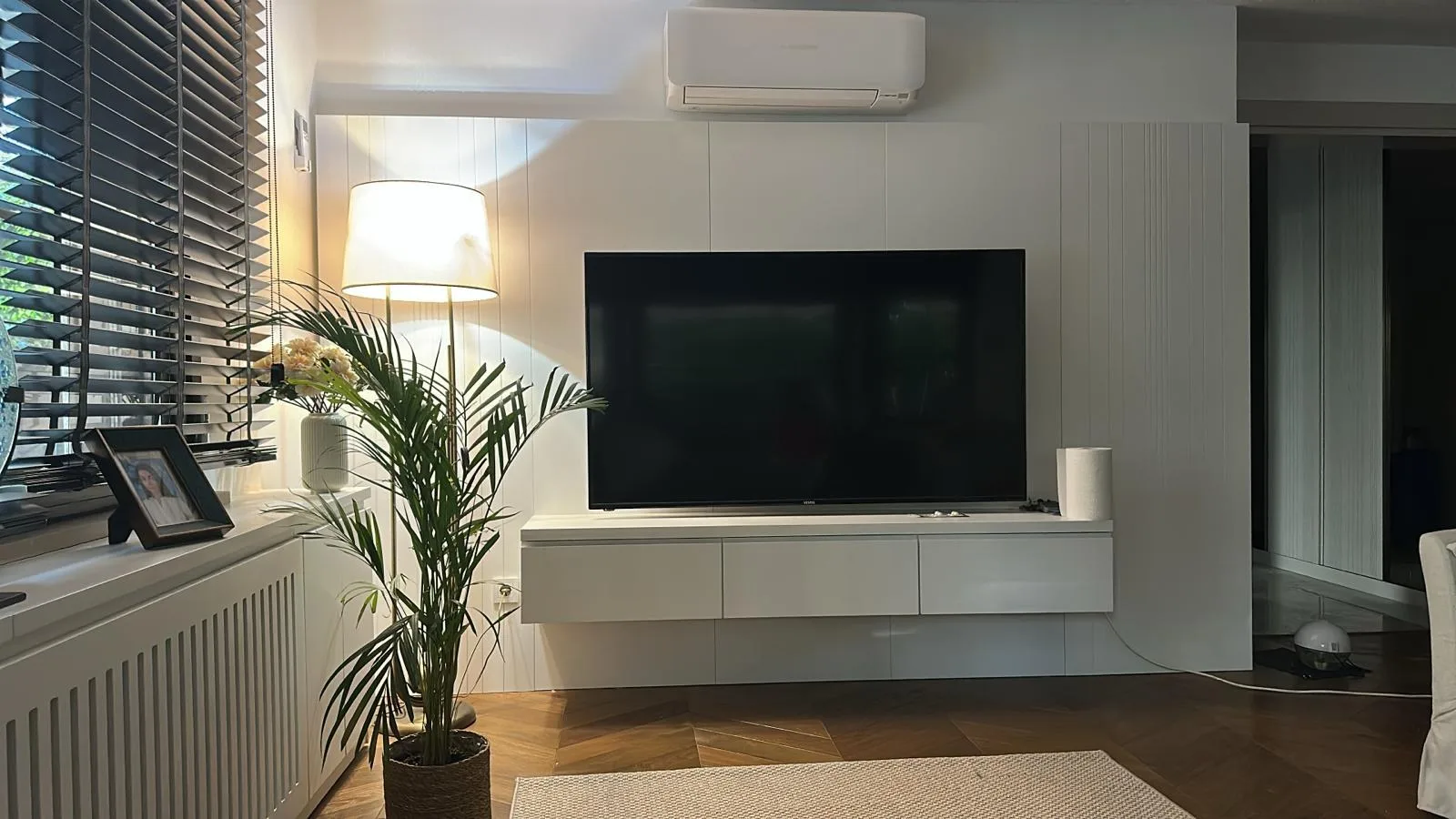 Beyaz duvara asılı sade TV ünitesi ve lambri panel