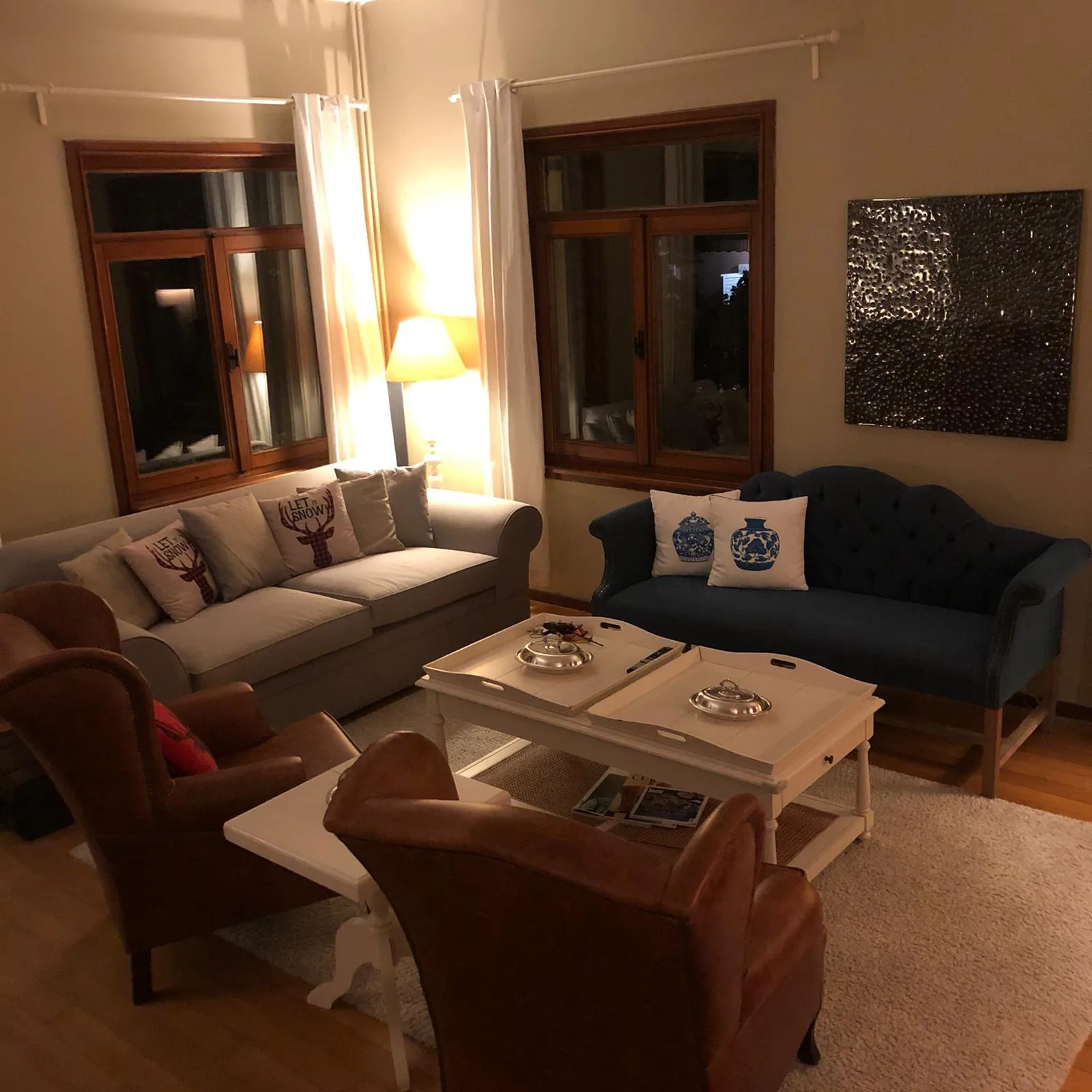 Lacivert kapitone kanepe, krem üçlü kanepe ve taba deri kulaklı berjerlerden oluşan salon düzeni